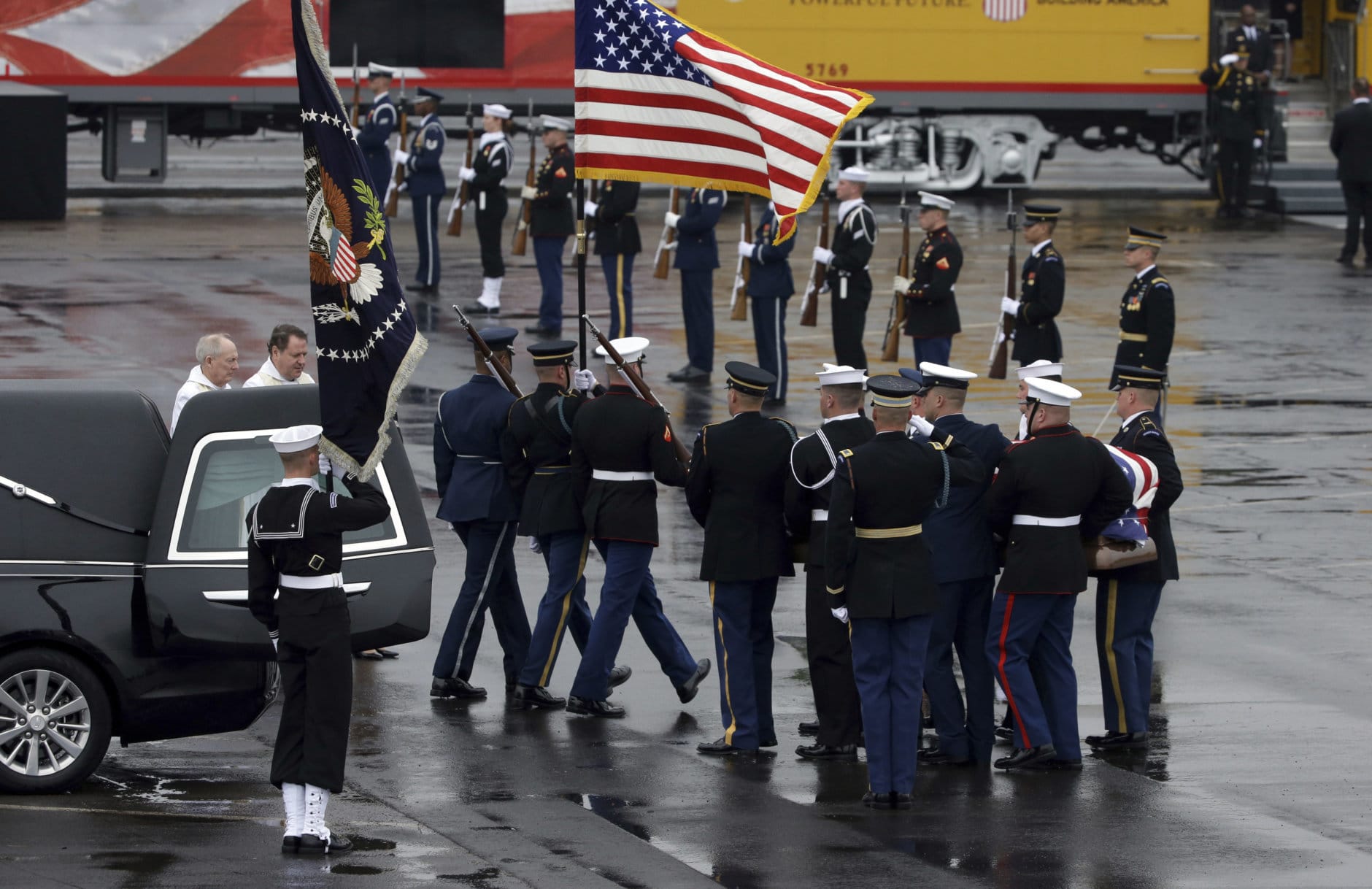 The flag-draped casket of former President George H.W. Bush is carried by a joint services military honor guard from a hearse at Union Pacific Westfield auto facility Thursday, Dec. 6, 2018, in Spring, Texas. (AP Photo/Kiichiro Sato)