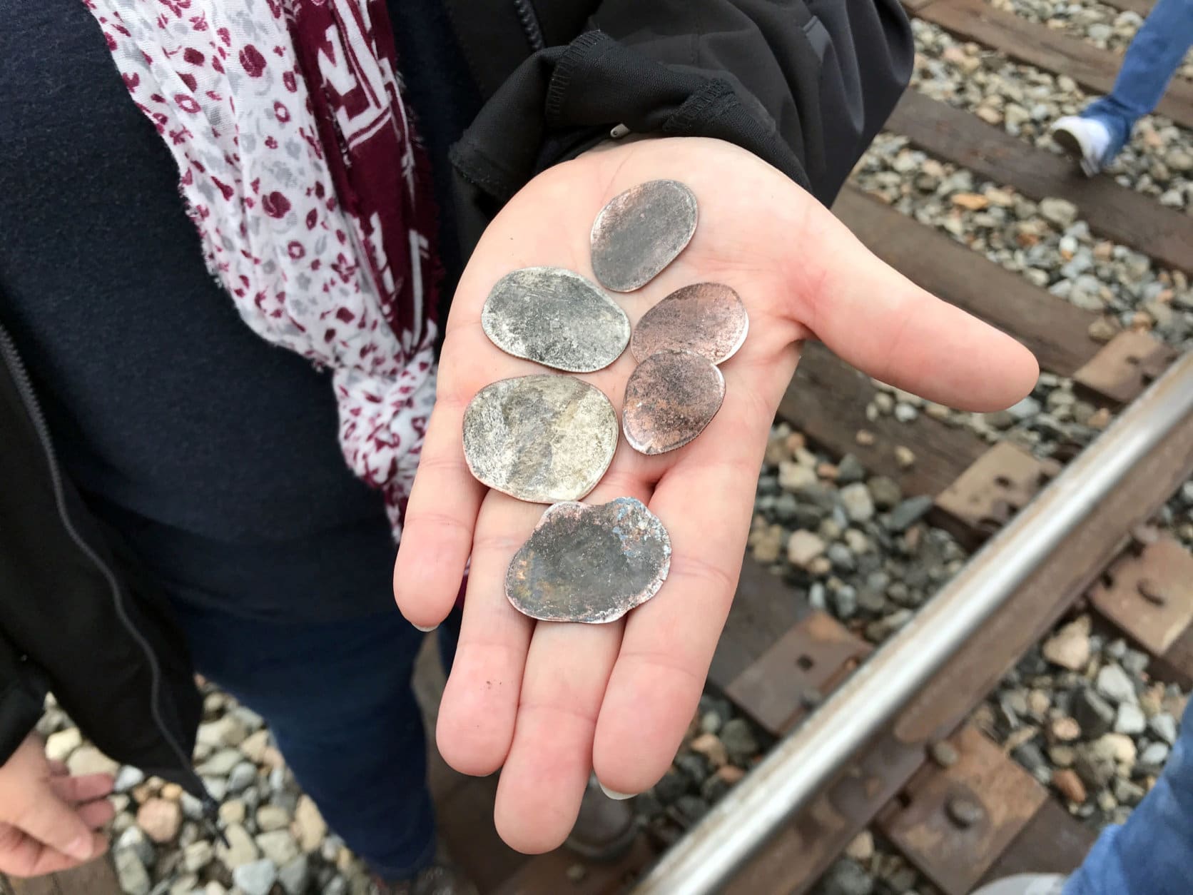 Ana Garza, of Cypress, Texas, displays coins flattened by the memorial train carrying the casket of President George H.W. Bush when it passed through Pinehurst, Texas, Thursday, Dec. 6, 2018. On Thursday, that same 4,300-horsepower machine left a suburban Houston railyard loaded with Bush's casket for his final journey after almost a week of ceremonies in Washington and Texas. (AP Photo/Nomaan Merchant)