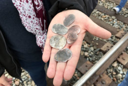 Ana Garza, of Cypress, Texas, displays coins flattened by the memorial train carrying the casket of President George H.W. Bush when it passed through Pinehurst, Texas, Thursday, Dec. 6, 2018. On Thursday, that same 4,300-horsepower machine left a suburban Houston railyard loaded with Bush's casket for his final journey after almost a week of ceremonies in Washington and Texas. (AP Photo/Nomaan Merchant)