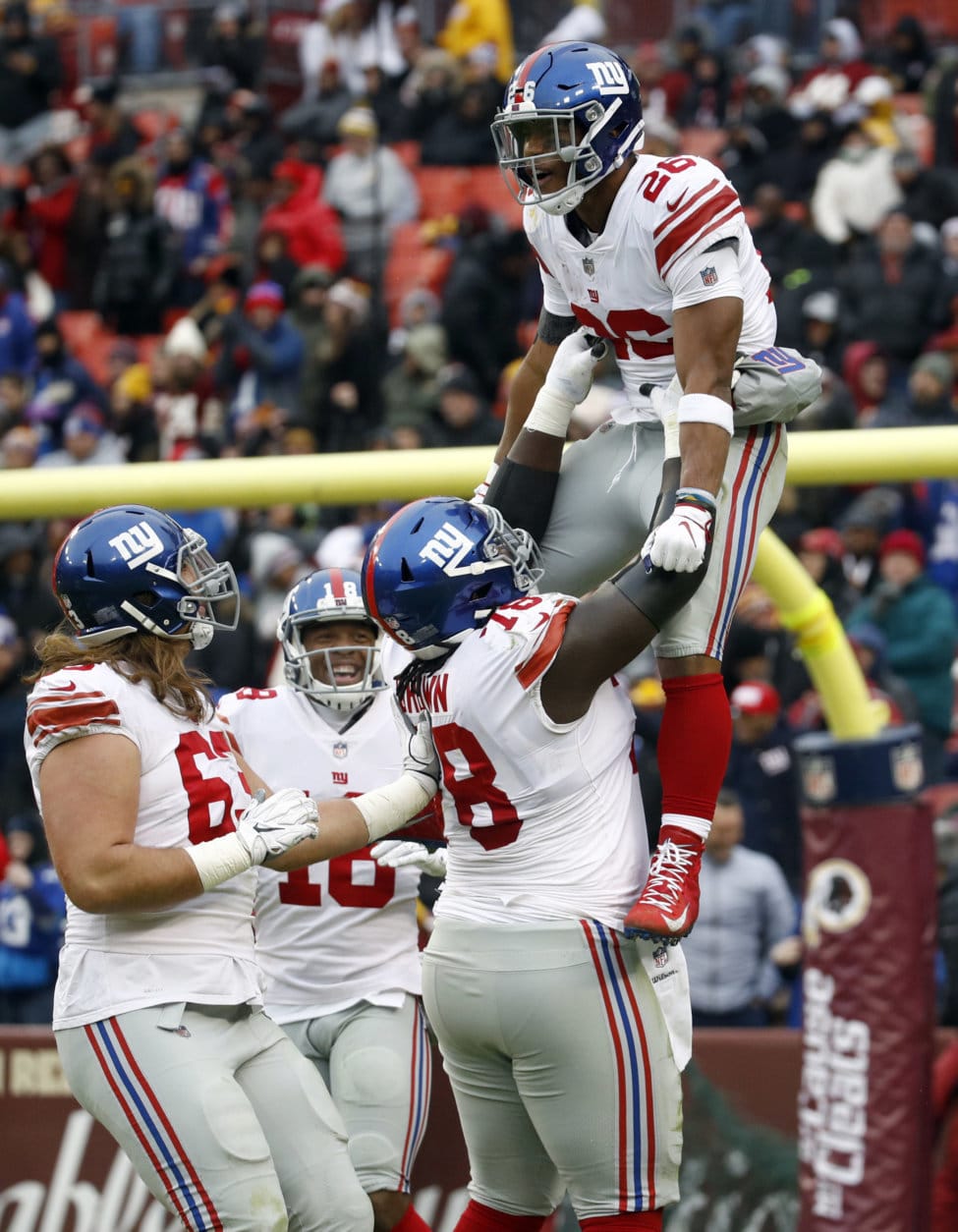 New York Giants running back Saquon Barkley (26) is picked up offensive guard Jamon Brown (78) as they celebrate his 78-yard touchdown during the first half of an NFL football game against the Washington Redskins, Sunday, Dec. 9, 2018, in Landover, Md. (AP Photo/Patrick Semansky)