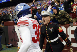 A United States Marine Corps sergeant, right, celebrates a run by New York Giants cornerback Antonio Hamilton (30) during the first half of an NFL football game against the Washington Redskins, Sunday, Dec. 9, 2018, in Landover, Md. (AP Photo/Patrick Semansky)