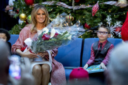 First lady Melania Trump is given flowers by Tearrianna Cooke-Starkey, left, and Nathan Simm, right, after she reads "Oliver the Ornament" to children at Children's National Health System, Thursday, Dec. 13, 2018, in Washington. (AP Photo/Andrew Harnik)