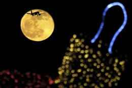 The moon shines  behind an illuminated Christmas ornament as an aircraft prepares for landing at the airport in southern coastal city of Larnaca, in the eastern Mediterranean island of Cyprus, Sunday, Dec. 23, 2018. (AP Photo/Petros Karadjias)