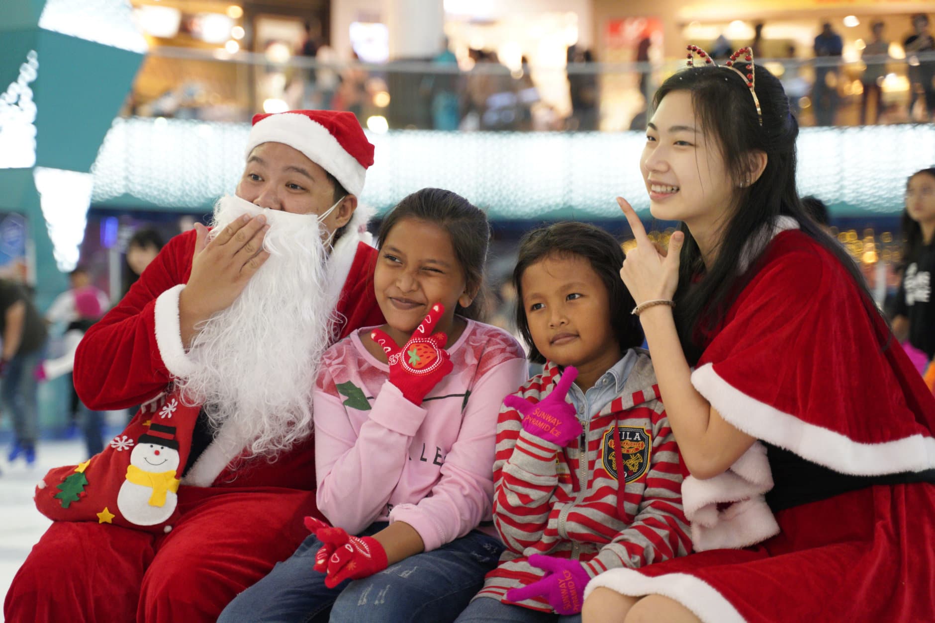 A man dressed as Santa Claus poses with children on Christmas Eve at a shopping mall in Petaling Jaya, Malaysia, Monday, Dec. 24, 2018. Shopping malls in the country have been decorated with Christmas trees, Santa Claus figures and illuminations to attract year-end shoppers. (AP Photo/Yam G-Jun)