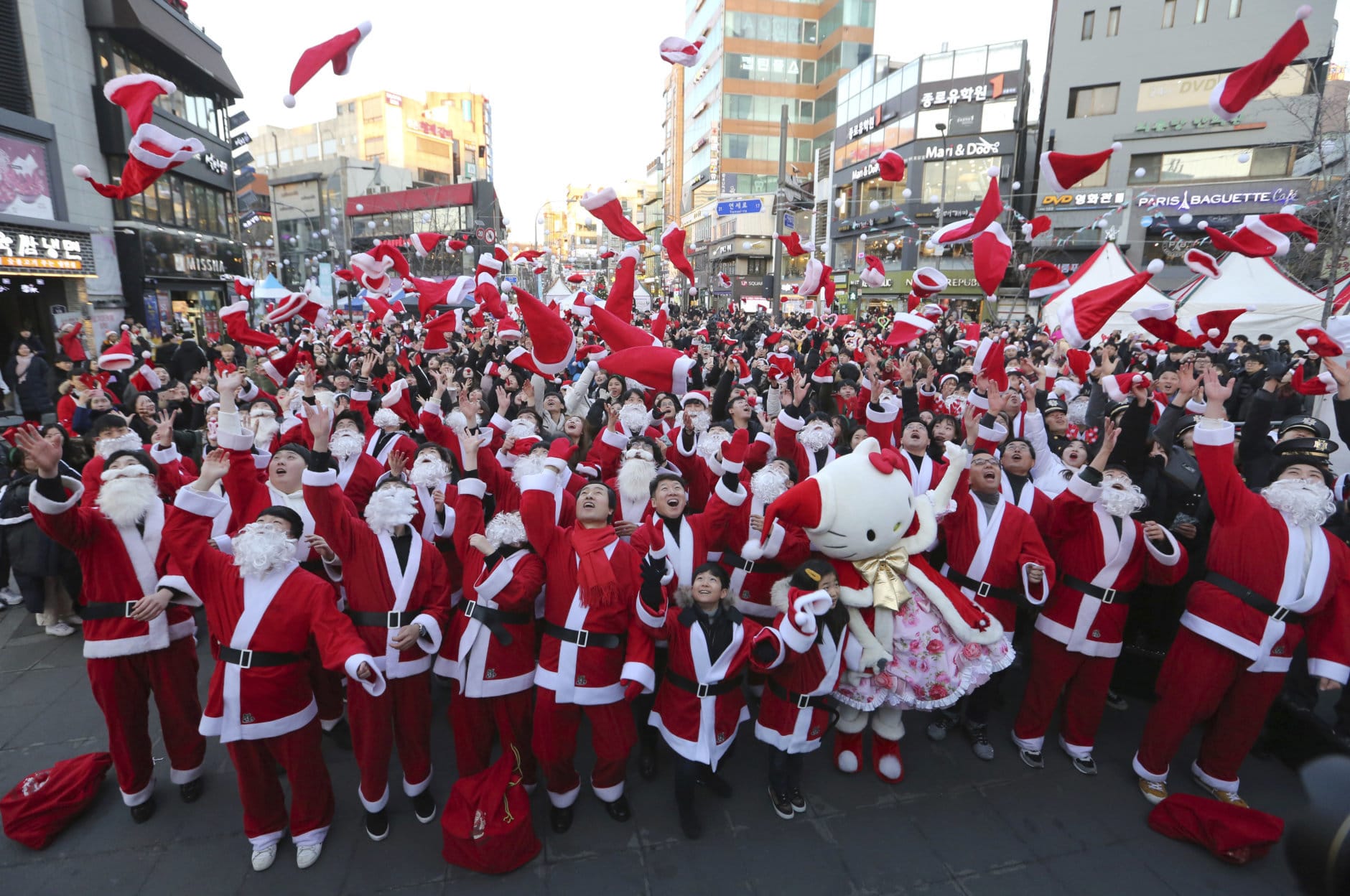 Volunteers clad in Santa Claus costumes throw their hats in the air as they gather to deliver gifts for the poor in downtown Seoul, South Korea, Monday, Dec. 24, 2018. (AP Photo/Ahn Young-joon)