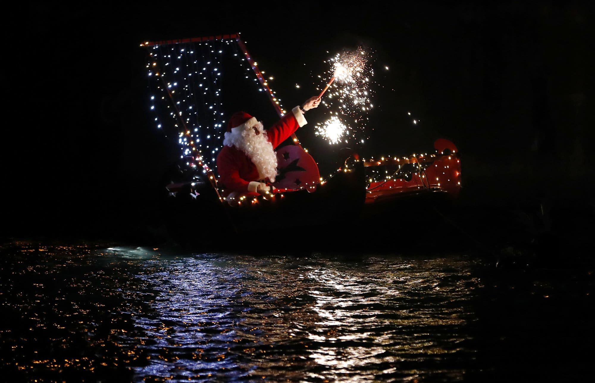A man dressed as Santa Claus holds a flare as he sits on a boat during a Christmas eve celebrations in Imperia, Italy, Monday, Dec. 24, 2018. (AP Photo/Antonio Calanni)