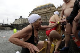 Bozena Cerna 88-year-old polar swimmer is helped from the water after participating in a traditional Christmas swim in the Vltava river in Prague, Czech Republic, Wednesday, Dec. 26, 2018. The National Theater is in the background. (AP Photo/Petr David Josek)