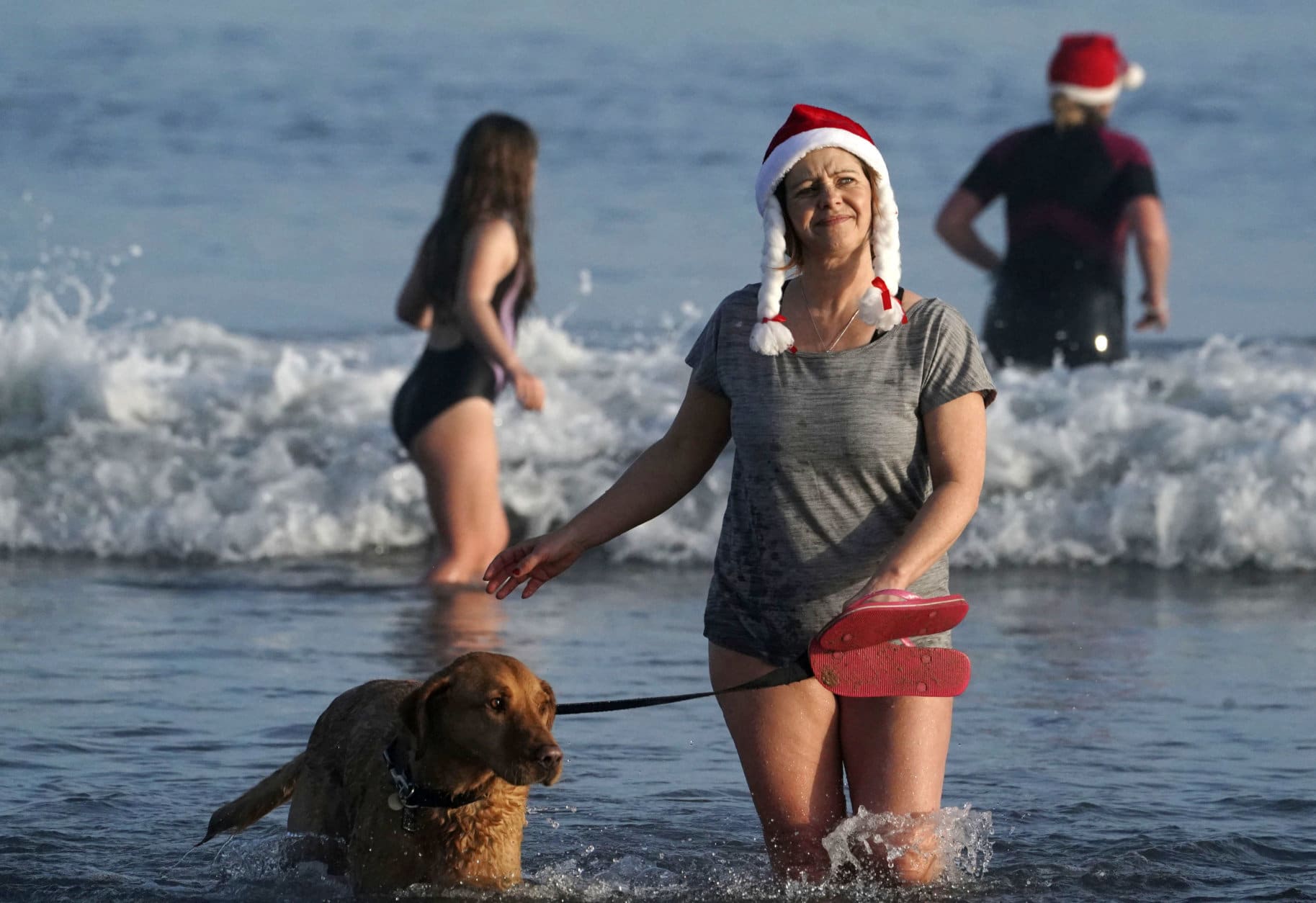 A woman and her dog take part in the traditional Boxing Day swim at Tynemouth beach in north east England, Wednesday Dec. 26, 2018. (Owen Humphreys/PA via AP)
