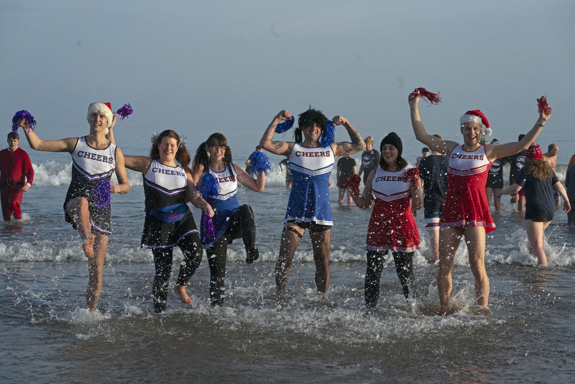Revellers in cheerleader costumes take part in the traditional Boxing Day swim at Tynemouth beach in north east England, Wednesday Dec. 26, 2018. (Owen Humphreys/PA via AP)