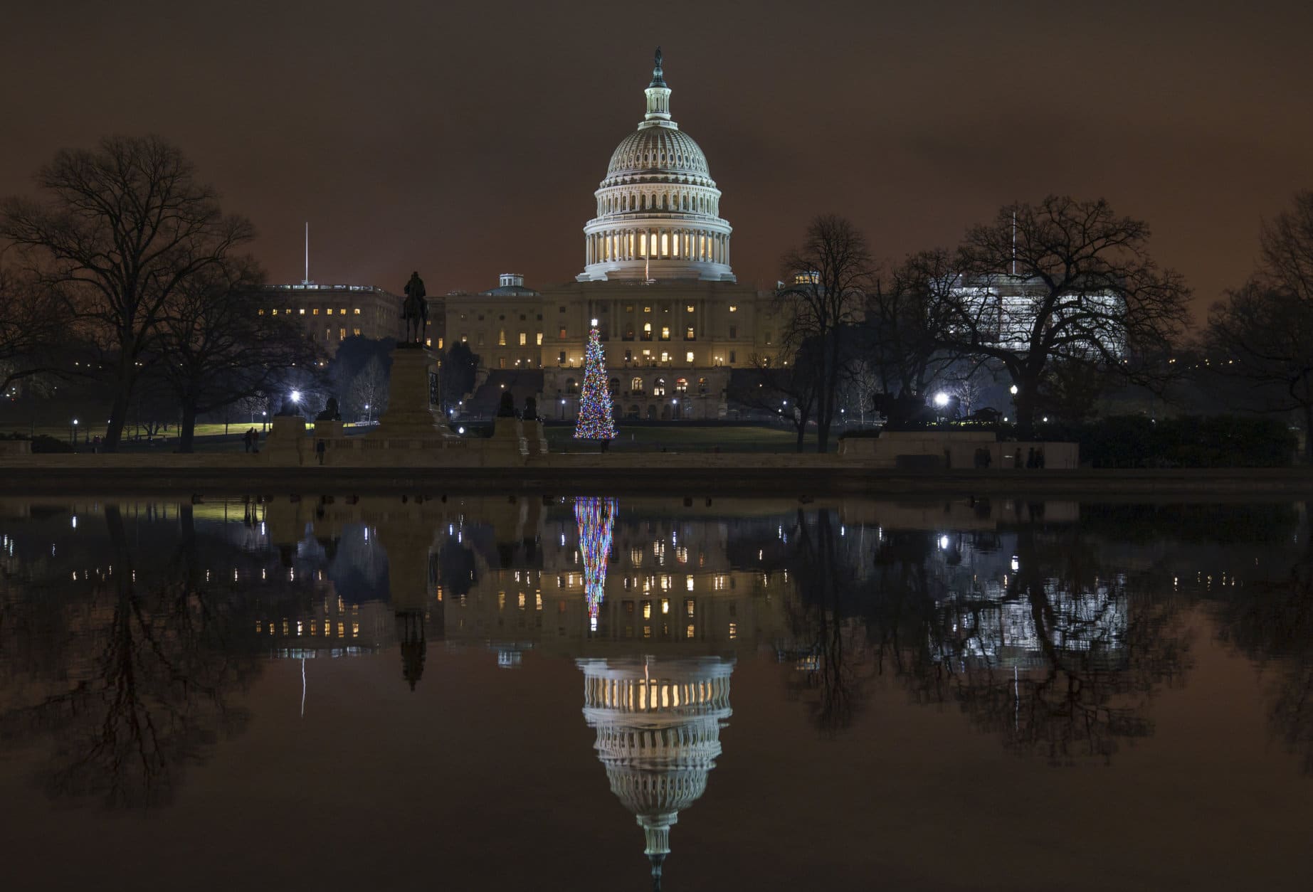 The Capitol is mirrored in the Reflecting Pool in Washington, as a partial government shutdown heads into a second week, Friday night, Dec. 28, 2018. Both chambers of Congress are gone, likely leaving the impasse till next week when the Democrats take control of the House of Representatives. (AP Photo/J. Scott Applewhite)