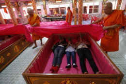 Monks cover worshippers lying in coffins at the Takien temple in suburban Bangkok, Thailand Monday, Dec. 31, 2018. Worshippers believe that the coffin ceremony – symbolizing death and rebirth – helps them rid themselves of bad luck and are born again for a fresh start in the new year. (AP Photo/Sakchai lalit)