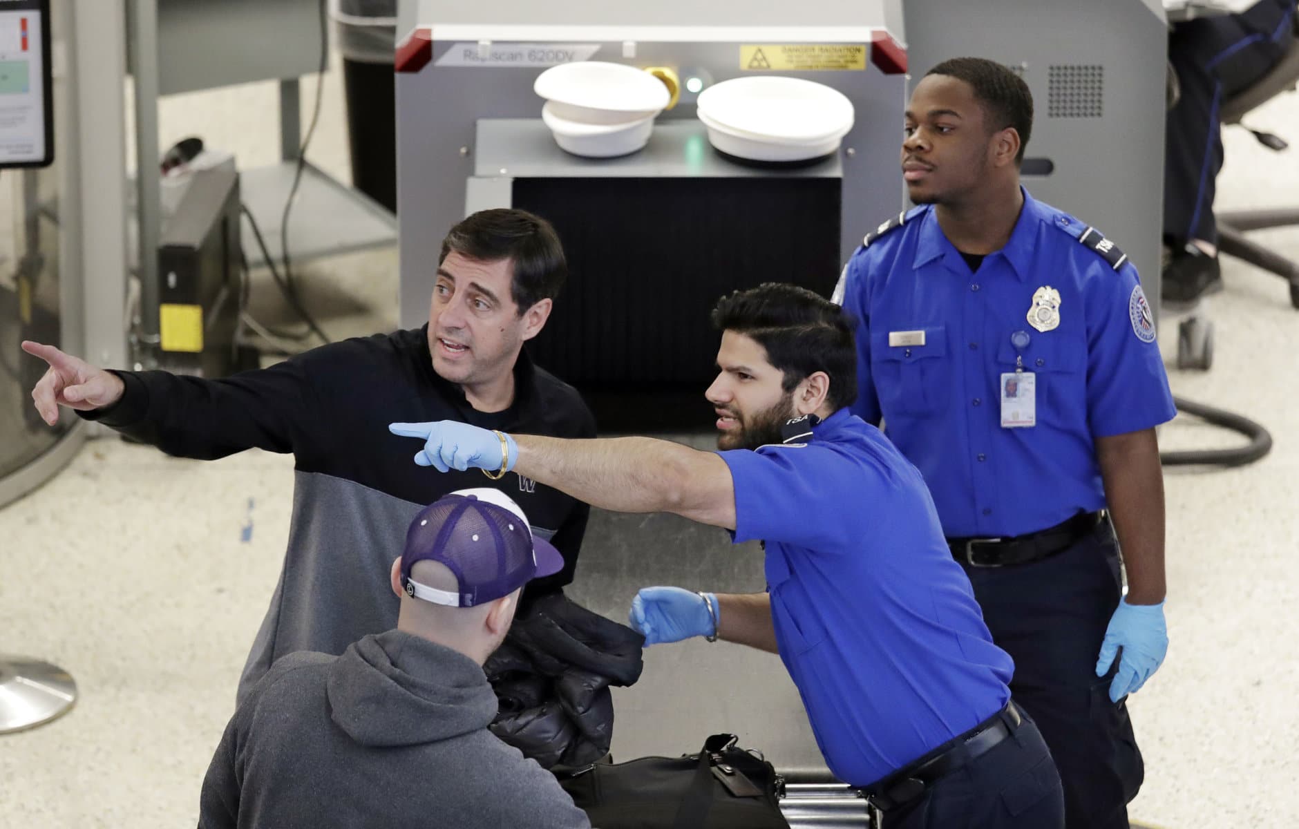 A Transportation Security Administration (TSA) officer directs a traveler as another looks on at a security screening area during a partial federal government shutdown Monday, Dec. 31, 2018, in SeaTac, Wash. TSA staff are among tens of thousands of federal employees considered essential as the federal government shutdown moves into its second week. They are working without pay until the shutdown ends, but will likely be paid retroactively later on. (AP Photo/Elaine Thompson)