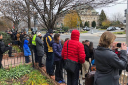 People line Wisconsin Avenue across the street from the Washington National Cathedral as the procession for former President George H.W. Bush approaches. (WTOP/John Aaron)