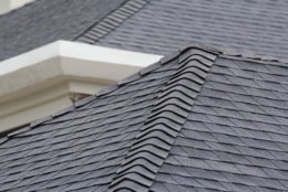 edge of Roof shingles on top of the house, dark asphalt tiles on the roof background.