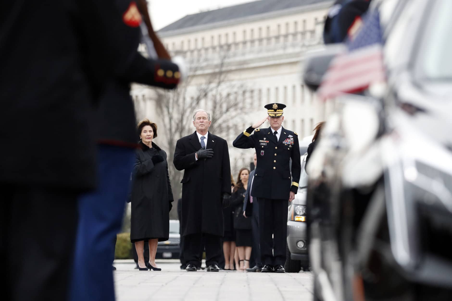 Former President George W. Bush and former first lady Laura Bush put their hands over their hearts as a joint services military honor guard carries the flag-draped casket of former U.S. President George H. W. Bush from the U.S. Capitol to transport it to Washington National Cathedral December 5, 2018 in Washington, DC. President Bush will be buried at his final resting place at the George H.W. Bush Presidential Library at Texas A&amp;M University in College Station, Texas. A WWII combat veteran, Bush served as a member of Congress from Texas, ambassador to the United Nations, director of the CIA, vice president and 41st president of the United States.  (Photo by Alex Brandon - Pool/Getty Images)