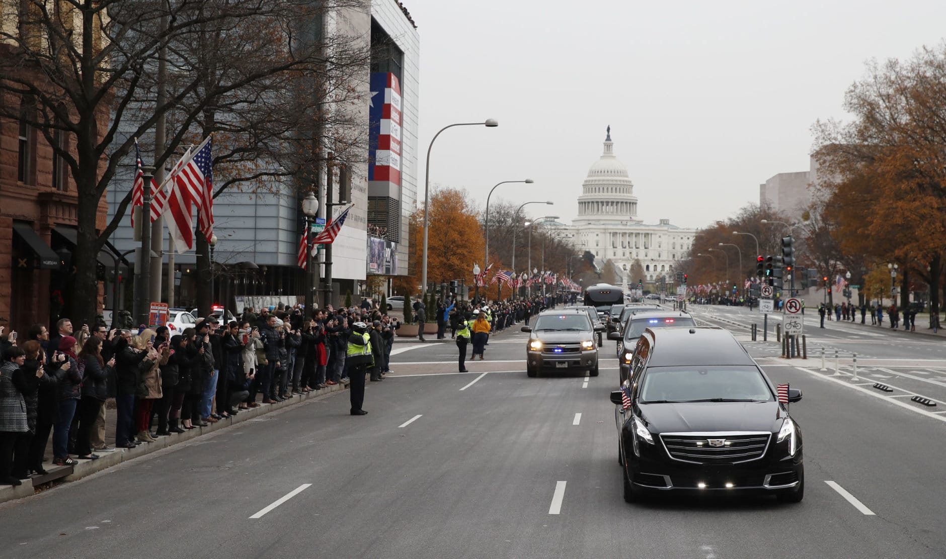 People line Pennsylvania Ave. as the hearse passes by carrying the flag-draped casket of former President George H.W. Bush as it drives away from the Capitol heading to a State Funeral at the National Cathedral on December 5, 2018 in Washington, DC. President Bush will be buried at his final resting place at the George H.W. Bush Presidential Library at Texas A&amp;M University in College Station, Texas. A WWII combat veteran, Bush served as a member of Congress from Texas, ambassador to the United Nations, director of the CIA, vice president and 41st president of the United States.  (Photo by Alex Brandon - Pool/Getty Images)