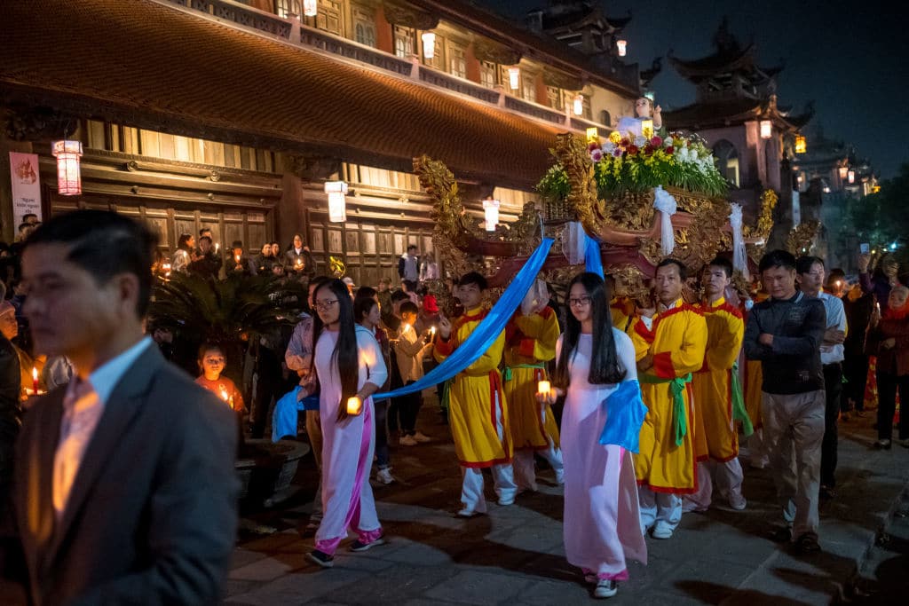 NINH BINH, VIETNAM - DECEMBER 24:  Pilgrims and locals take part in the procession of Baby Jesus led by Bishop Joseph Nguyen Nang during the Christmas Midnight Mass on the site of Phat Diem Cathedral on December 24, 2018 in Kim Son District, Ninh Binh Province, Vietnam. Phat Diem Cathedral, located about 120 kilometers from Hanoi to the south, in an area that has been a stronghold of Christianity in Vietnam since Portuguese missionaries began proselytizing Vietnam in the sixteenth century. This Catholic church was built in the 1875s to 1898s, with oriental architecture mixing Western architectural style and Vietnamese religious buildings. As a predominantly Buddhist nation, Christmas is not an official public holiday in Vietnam but many people have adopted to celebrate it both as a religious festival and a new cultural tradition.  (Photo by Linh Pham/Getty Images)