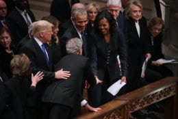 Former U.S. President George W. Bush (C) leans across President Donald Trump and first lady Melania Trump to greet fellow former presidents Barack Obama, Bill Clinton and former first ladies Rosalynn Carter, Hillary Clinton and Michelle Obama during the state funeral for his father and former President George H.W. Bush at the National Cathedral December 05, 2018 in Washington, DC. A WWII combat veteran, Bush served as a member of Congress from Texas, ambassador to the United Nations, director of the CIA, vice president and 41st president of the United States.  (Photo by Chip Somodevilla/Getty Images)