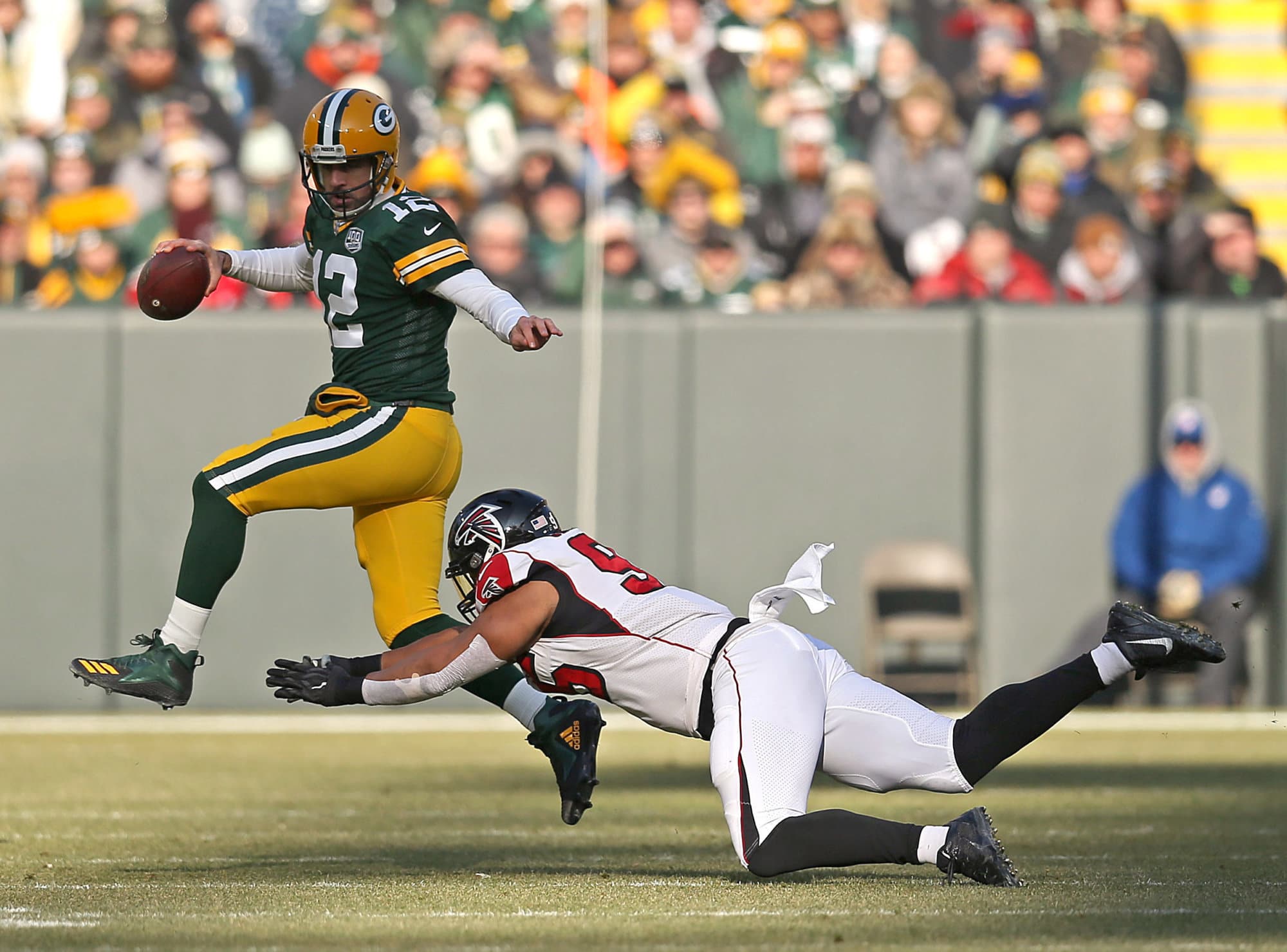 GREEN BAY, WISCONSIN - DECEMBER 09:  Aaron Rodgers #12 of the Green Bay Packers evades a diving Jack Crawford #95 of the Atlanta Falcons during the first half of a game at Lambeau Field on December 09, 2018 in Green Bay, Wisconsin. (Photo by Dylan Buell/Getty Images)