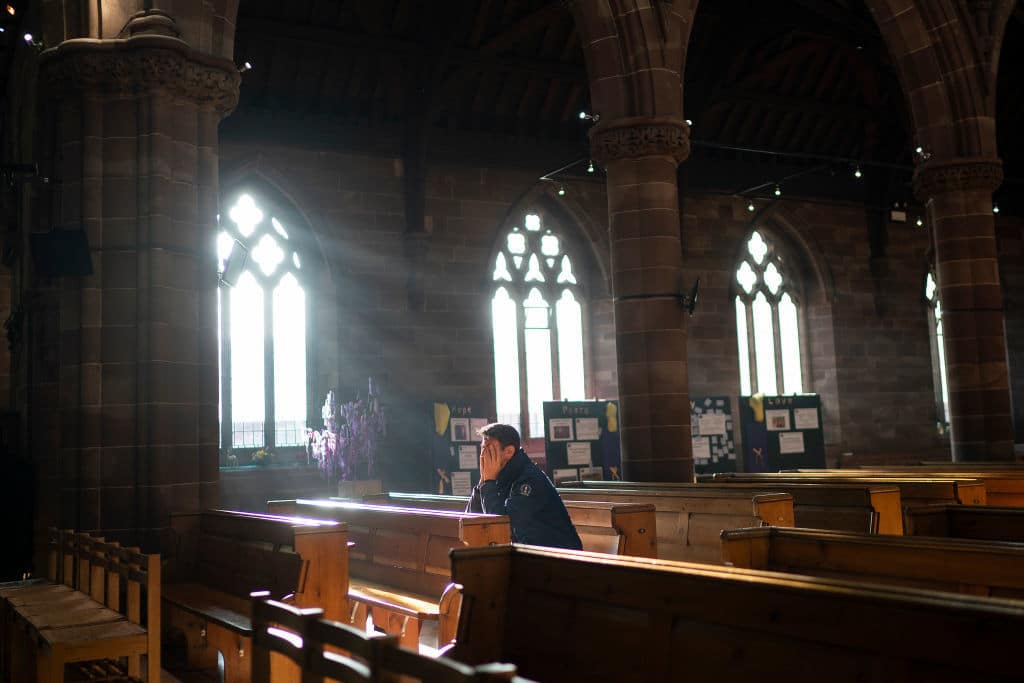 BIRMINGHAM, ENGLAND - DECEMBER 24: A man prays in a church as shoppers make their last minute purchases on Christmas Eve on December 24, 2018 in Birmingham, England. Financial management consultancy Deloitte has predicted larger than normal discounts for boxing day sales as retailers aim to recuperate sales after a weak lead up to Chrismas. (Photo by Christopher Furlong/Getty Images)