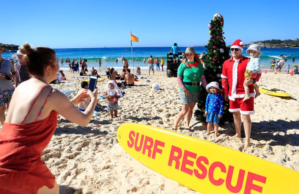 SYDNEY, AUSTRALIA - DECEMBER 25: Families pose by a Christmas tree on Bondi Beach on December 25, 2018 in Sydney, Australia. December is one of the hottest months of the year across Australia, with Christmas Day traditionally involving a trip to the beach and celebrations outdoors. (Photo by Mark Evans/Getty Images)