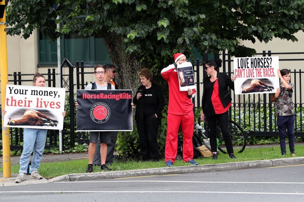 AUCKLAND, NEW ZEALAND - DECEMBER 26: A small group of protesters stand at the entrance during the Boxing Day Races at Ellerslie Racecourse on December 26, 2018 in Auckland, New Zealand. Activists are calling on racegoers to reconsider supporting horse racing and demanding the industry implement a retirement plan for all racehorses. (Photo by Dave Rowland/Getty Images)