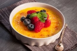 gorgeous French dessert Creme brulee served with berries and a silver spoon