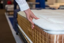 Close-up of female hand touching and testing mattress in a store. Copy space.