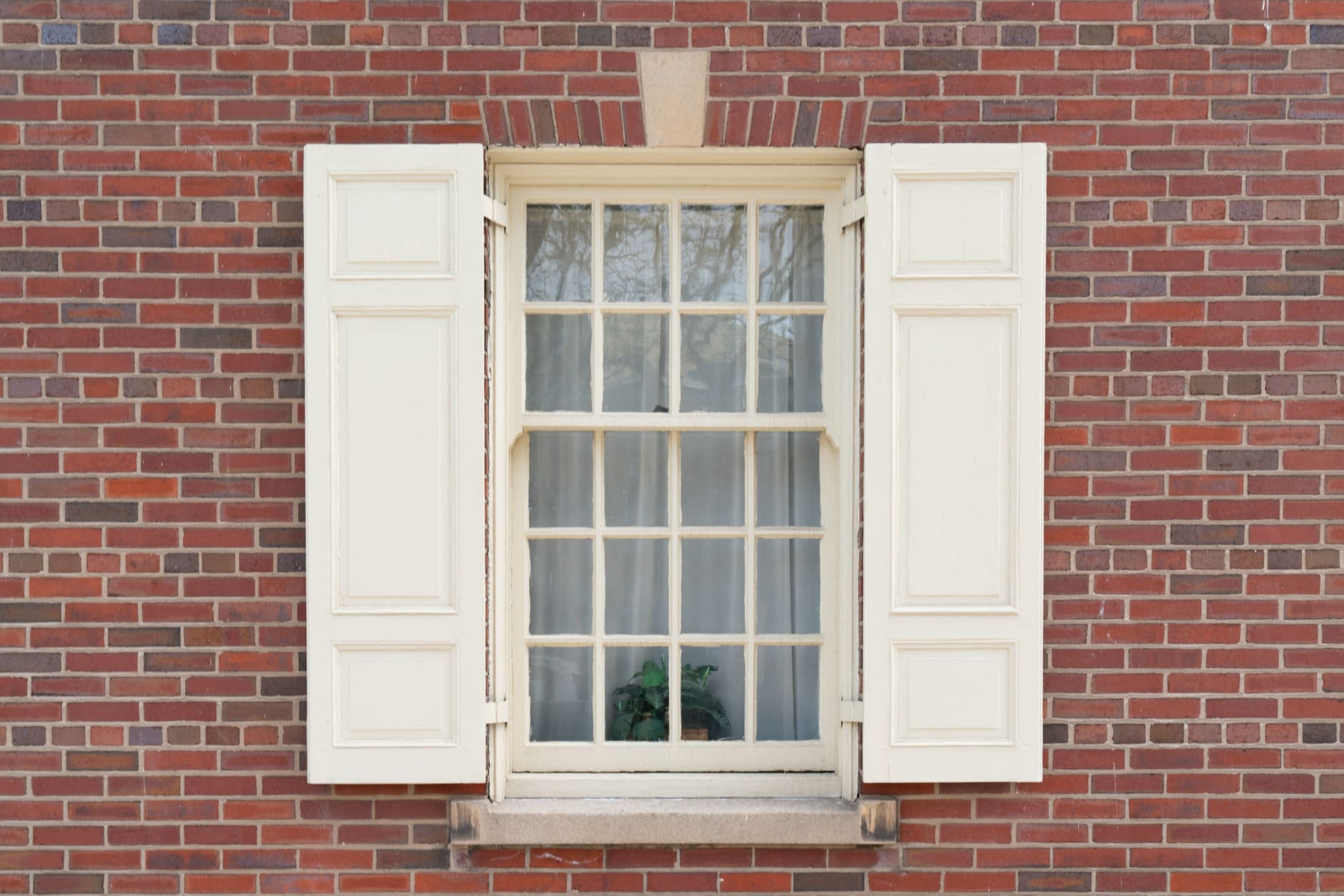 Old colonial window with shutters on historic brick building