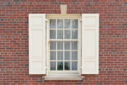 Old colonial window with shutters on historic brick building