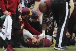 Washington Redskins quarterback Alex Smith (11) lays on the ground as teammate Adrian Peterson, right, holds his hand after an injury during the second half of an NFL football game against the Houston Texans, Sunday, Nov. 18, 2018 in Landover, Md. Smith broke his right tibia and fibula on a sack by Texans' Kareem Jackson. (AP Photo/Pablo Martinez Monsivais)