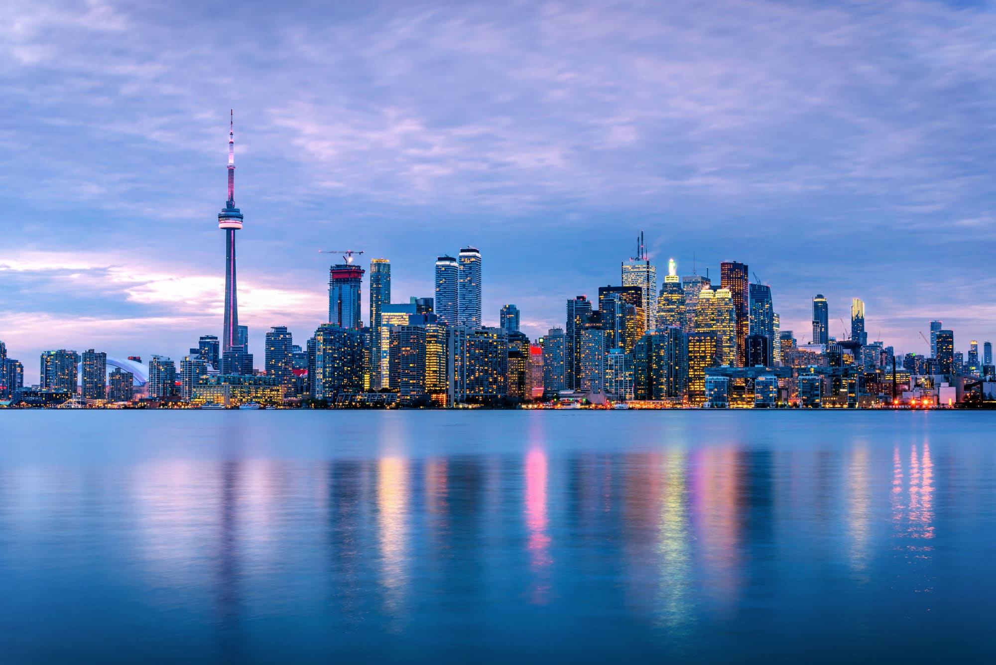 Spectacular View of Downtown Toronto under Cloudy Sky at Dusk with Lights Reflecting in Water. Ontario, Canada.
