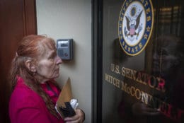 Reese Greer, a furloughed census worker, stands at the locked door of U.S. Sen. Mitch McConnell's office in Lexington, Ky., Wednesday, Jan 23, 2019, during a government shutdown protest. (AP Photo/Bryan Woolston)