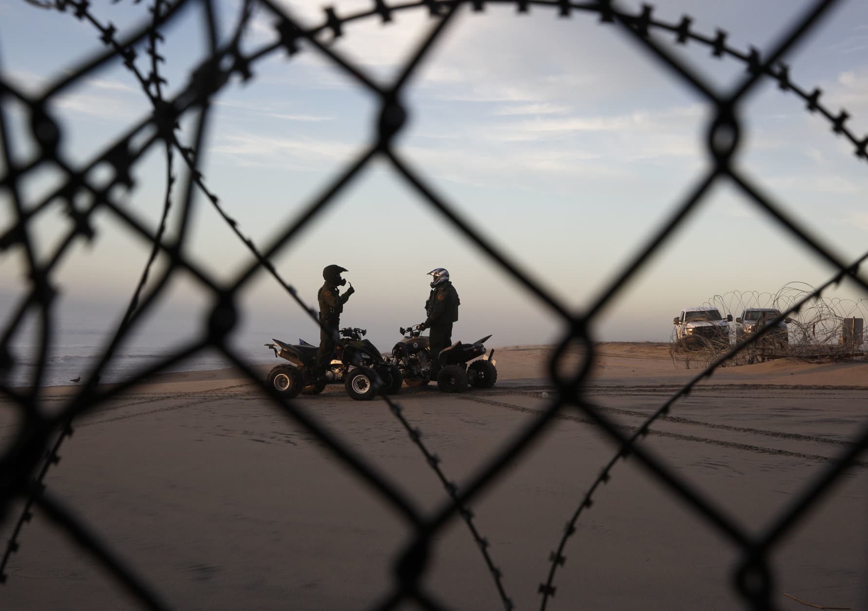 Two U.S. Border Patrol agents talk along the beach in San Diego, Wednesday, Jan. 9, 2019, seen through razor wire lining the border wall from Tijuana, Mexico. U.S. President Donald Trump walked out of his negotiating meeting with congressional leaders Wednesday — "I said bye-bye," he tweeted— as efforts to end the 19-day partial government shutdown fell into deeper disarray over his demand for billions of dollars to build a wall on the U.S.-Mexico border. (AP Photo/Gregory Bull)