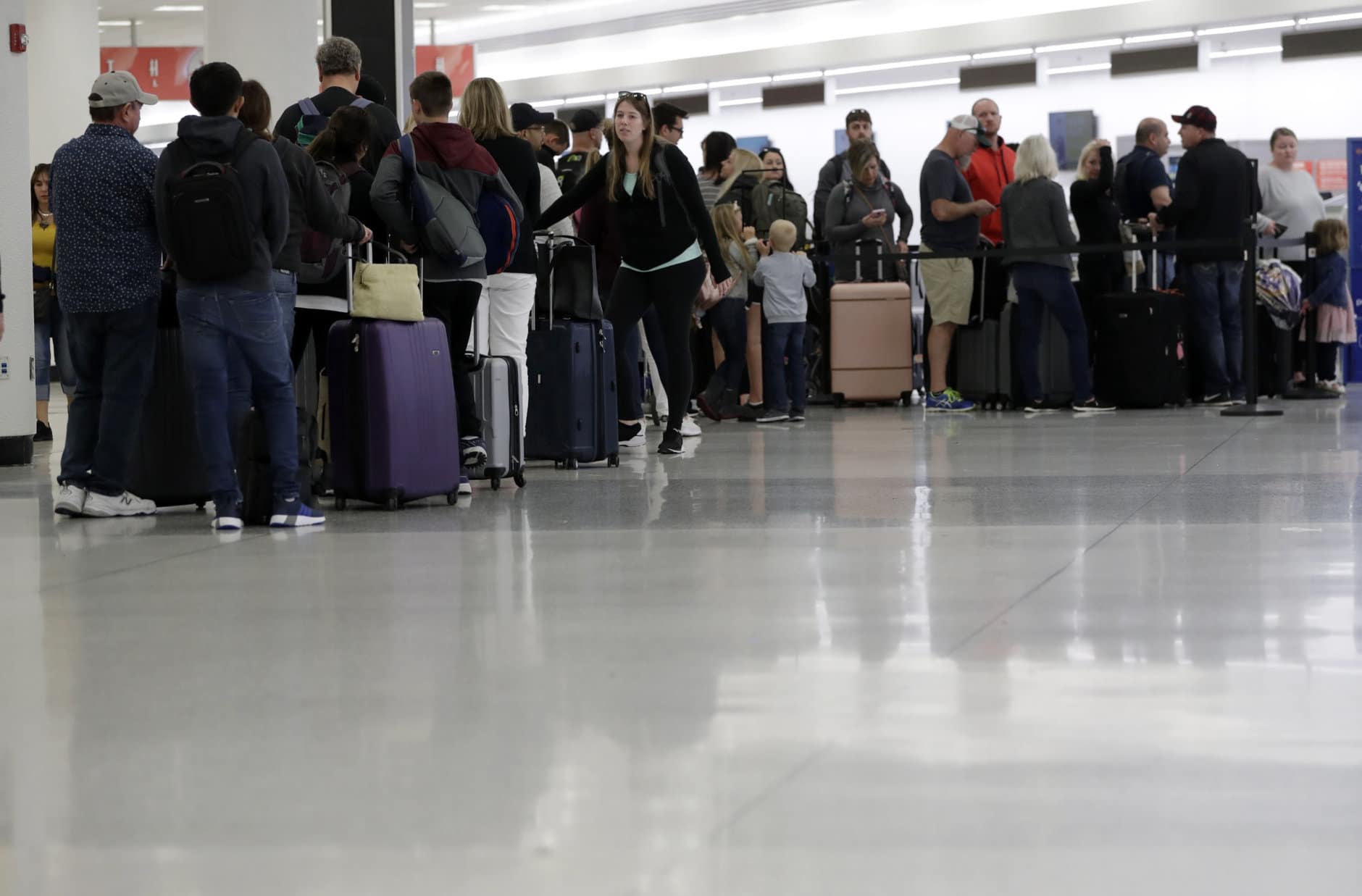 Passengers wait in line at Sun Country Airlines in Terminal G at Miami International Airport, Friday, Jan. 11, 2019, in Miami. The airport is closing Terminal G this weekend as the federal government shutdown stretches toward a fourth week because security screeners have been calling in sick at twice the airport's normal rate. (AP Photo/Lynne Sladky)