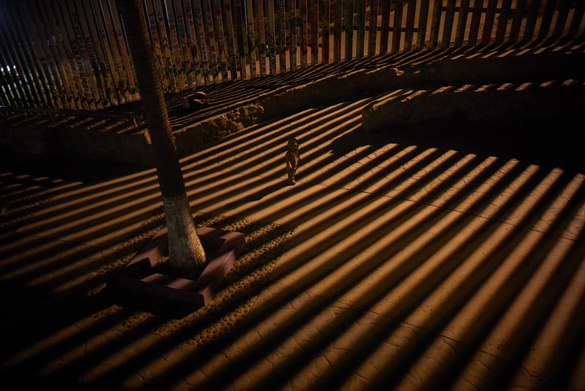 A boy plays as floodlights from the United States filter through the border wall Friday, Jan. 11, 2019, in Tijuana, Mexico. The partial U.S. government shutdown was on track Friday to become the longest closure in U.S. history as President Donald Trump and nervous Republicans look for a way out of the mess. A solution couldn't come soon enough for federal workers who got pay statements Friday but no pay. (AP Photo/Gregory Bull)