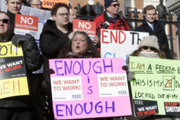 Internal Revenue Service employees, front row from the left, Brian Lanouette, of Merrimack, N.H., Mary Maldonado, of Dracut, Mass., and Maria Zangari, of Haverhill, Mass., display placards during a rally by federal employees and supporters, Thursday, Jan. 17, 2019, in front of the Statehouse, in Boston, held to call for an end of the partial shutdown of the federal government. (AP Photo/Steven Senne)