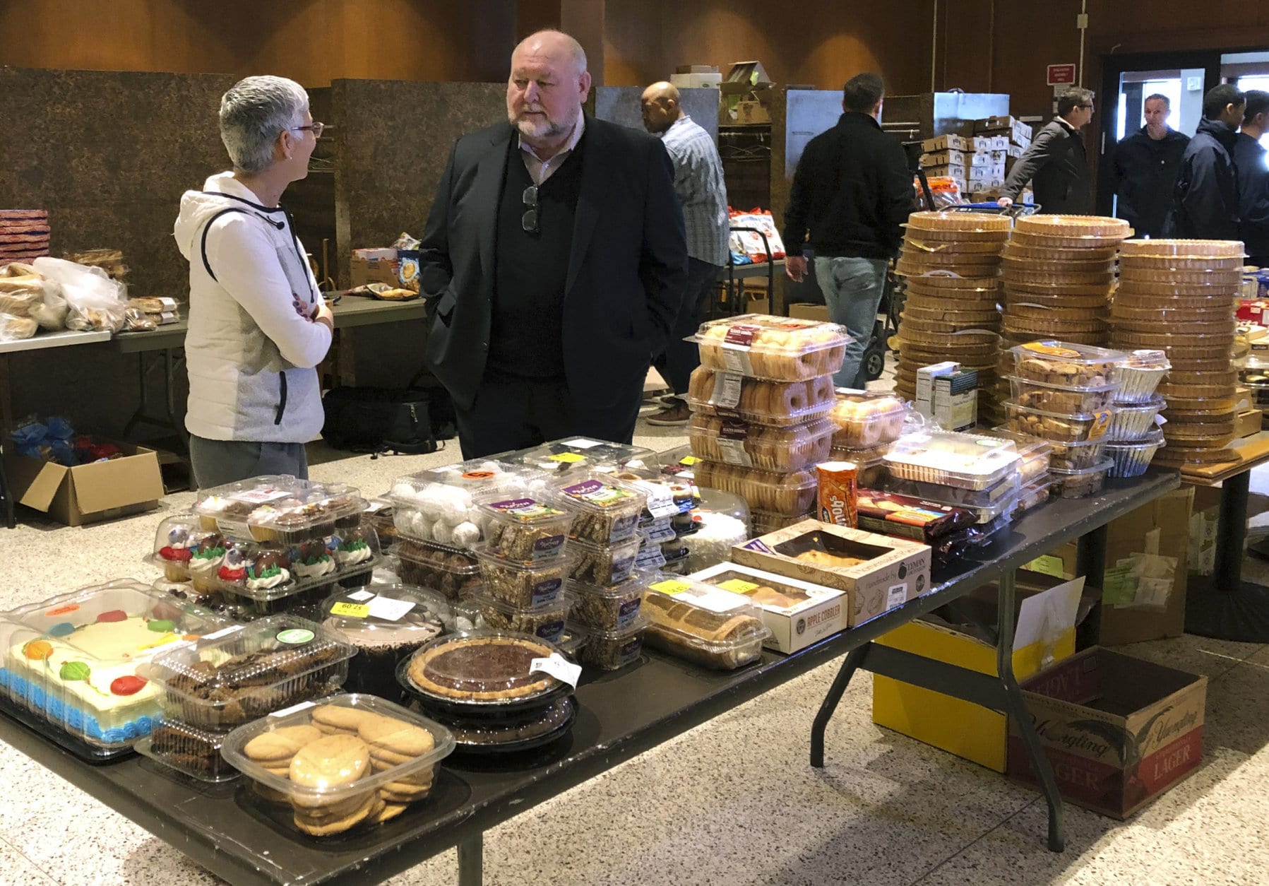 In this Thursday, Jan. 17, 2019 photo, retired U.S. Coast Guard Adm. Thad Allen, center, speaks with Felicitas Rendon, wife of Rear Adm. James E. Rendon, superintendent of the Coast Guard Academy in New London, Conn. Allen was visiting a pop-up food pantry created at a school to help hundreds of civilian and non-civilian Coast Guard employees affected by the partial federal government shutdown. Allen called the shutdown a "wound" that's been inflicted "by our own government." (AP Photo/Susan Haigh)