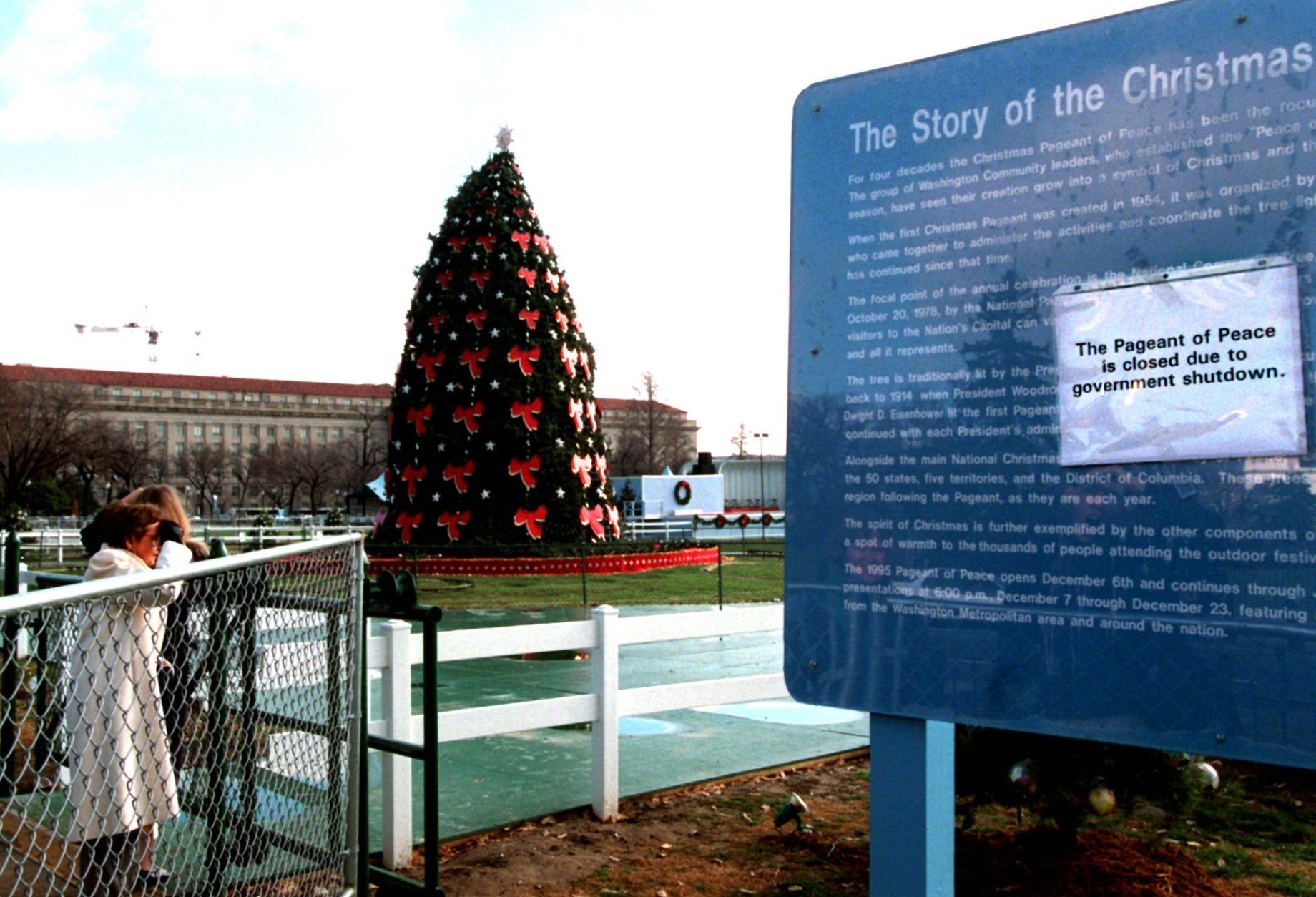 Tourists look at the national Christmas tree from behind locked gates Saturday Dec. 16, 1995 in Washington after the display was closed due to a federal budget shutdown. Parts of the federal government were ordered shut down today as President Clinton blamed the Republican Congress for attempting to force unacceptable cuts in programs affecting the lives of children, the elderly and the poor.  (AP Photo/Mark Wilson)