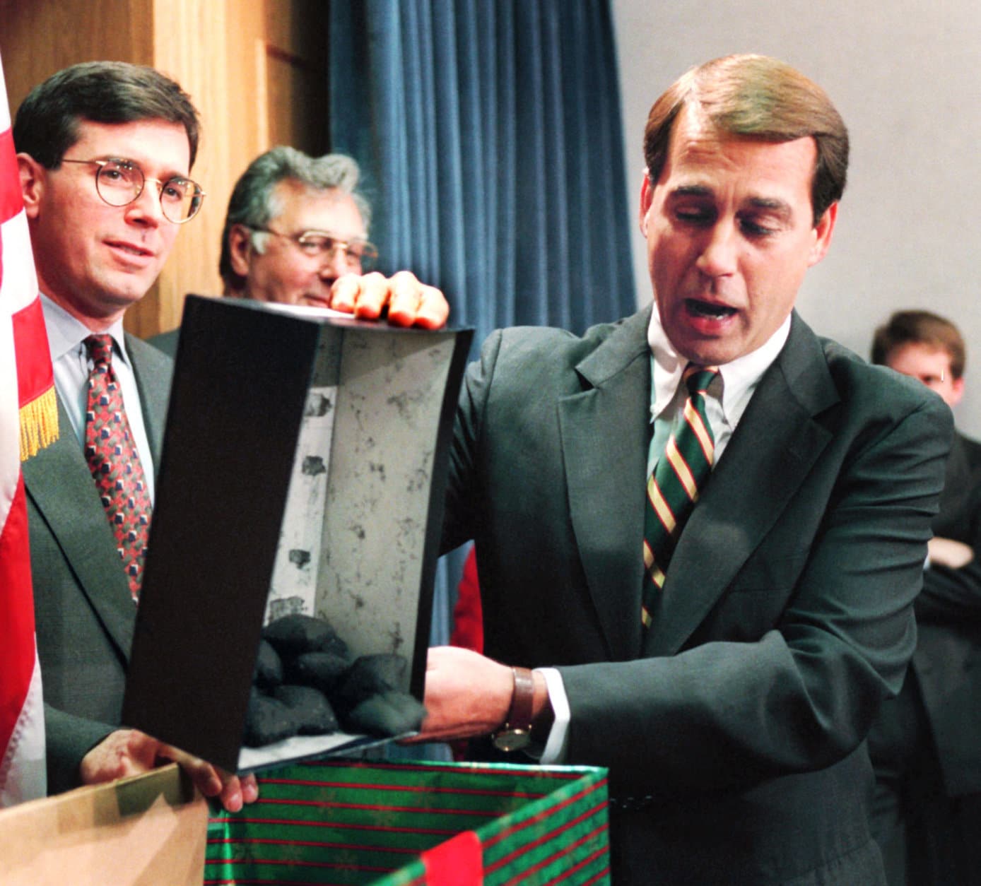 FILE - In this Dec. 21, 1995, file photo Rep. John Boehner, R-Ohio, dumps out coal, his so-called Christmas gift to President Clinton, during a news conference on the federal budget on Capitol Hill. The White House and Congressional Republicans tried to restart balanced budget talks after the sixth day of a partial government shutdown. Then, as now in 2011, a Democratic president clashed over spending priorities with a recently installed Republican House majority. (AP Photo/Denis Paquin, File)