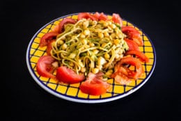 Food Dish on Black Wooden Background. Chickpeas, Spaghetti, Broccoli, Onions, Tomato. Yellow Blue Plate. Close Up.