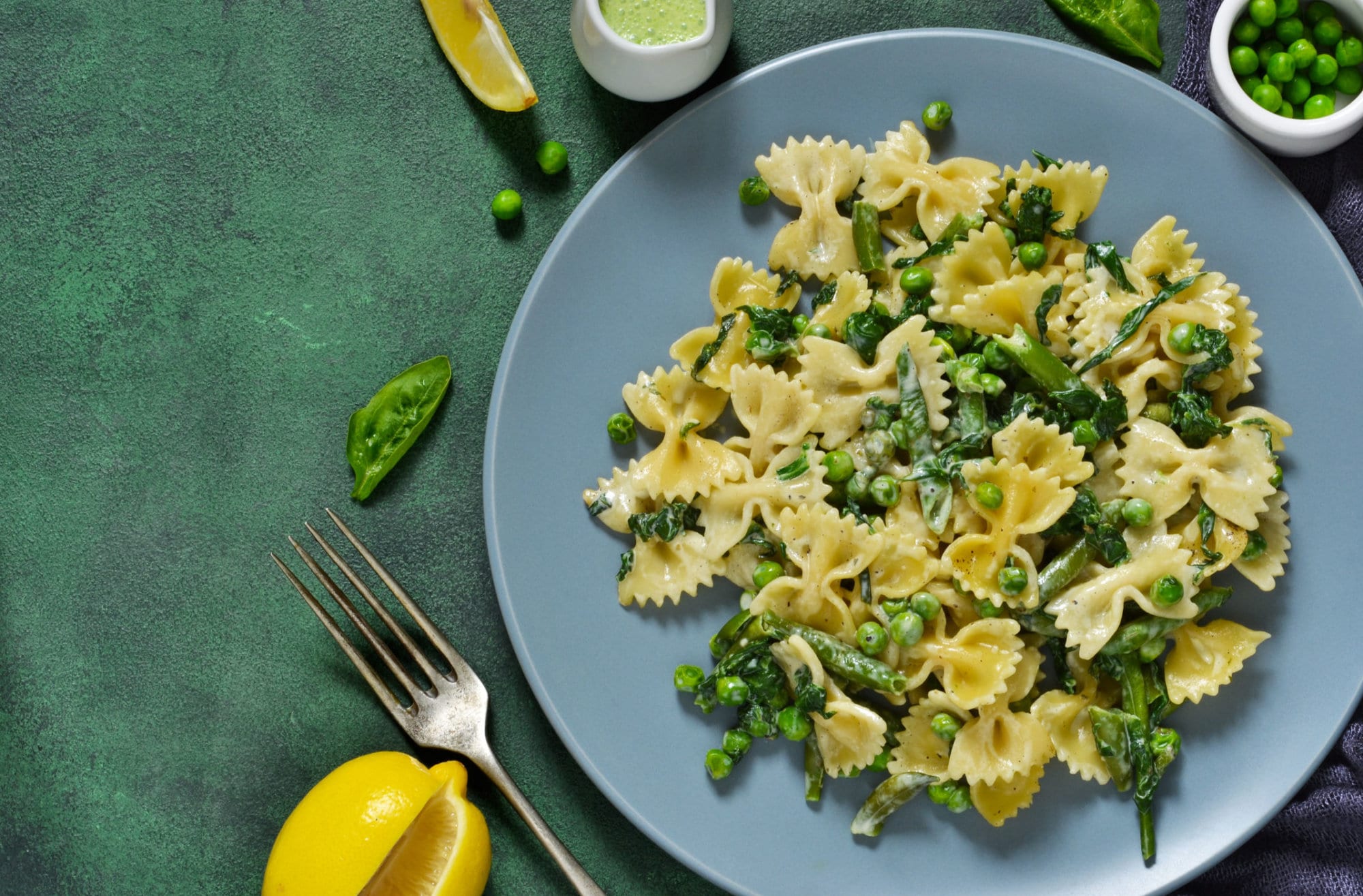Farfalle with asparagus sauce, green peas and spinach green background. Homemade dinner.