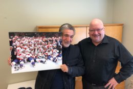 Leonsis never made it into the iconic championship photo, saying he was standing just outside the frame. So he posed with the photo, a copy of which rests in WTOP News & Program Director Mike McMearty's office. (WTOP/Julia Ziegler)