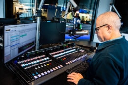 WTOP anchor Bruce Alan mans the Glass-Enclosed Nerve Center's new mixing board, which controls audio levels and can feed listener calls into the broadcast. (WTOP/Alejandro Alvarez)