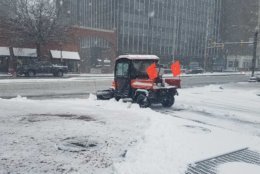 A plow fights the buildup of snow in Chevy Chase. (WTOP/Will Vitka)