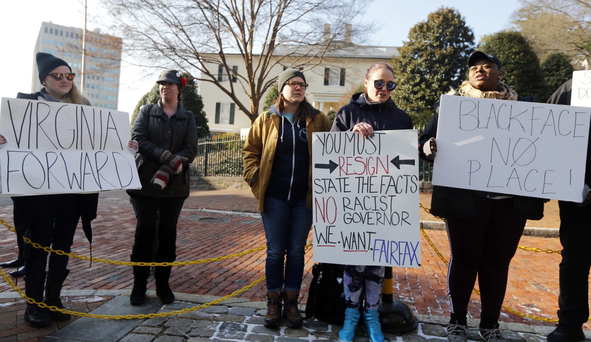 Demonstrators hold signs and chant outside the Governors Mansion at the Capitol in Richmond, Va., Saturday, Feb. 2, 2019. The demonstrators are calling for the resignation of Gov. Ralph Northam after a 30 year old photo of him on his medical school yearbook photo was widely distributed Friday. (AP Photo/Steve Helber)