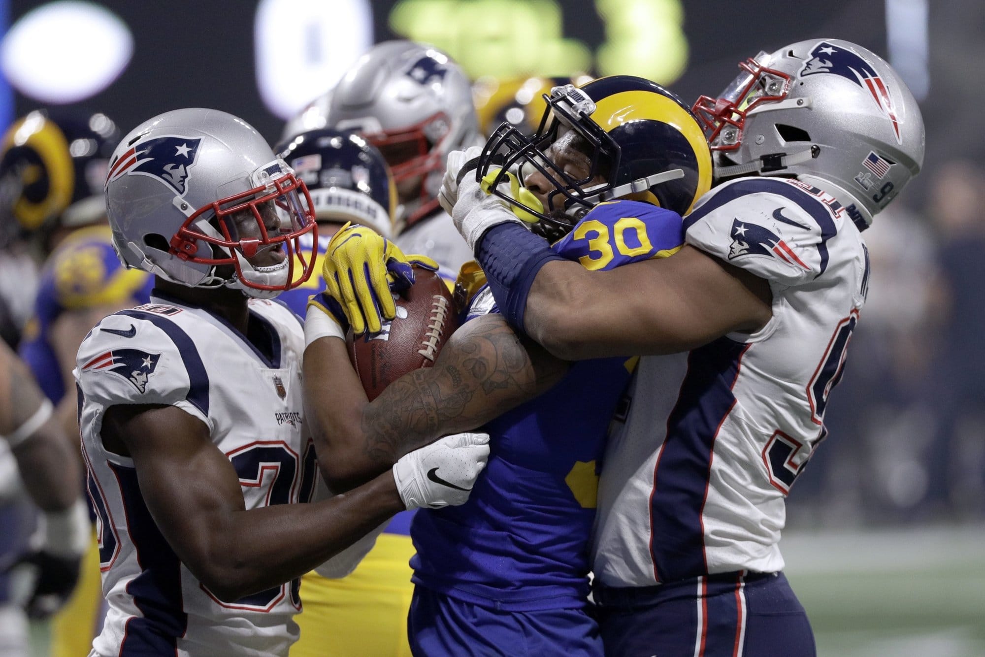 Los Angeles Rams' Todd Gurley II (30) is tackled by New England Patriots' Jason McCourty, left, and Deatrich Wise Jr., right, during the second half of the NFL Super Bowl 53 football game Sunday, Feb. 3, 2019, in Atlanta. (AP Photo/David J. Phillip)