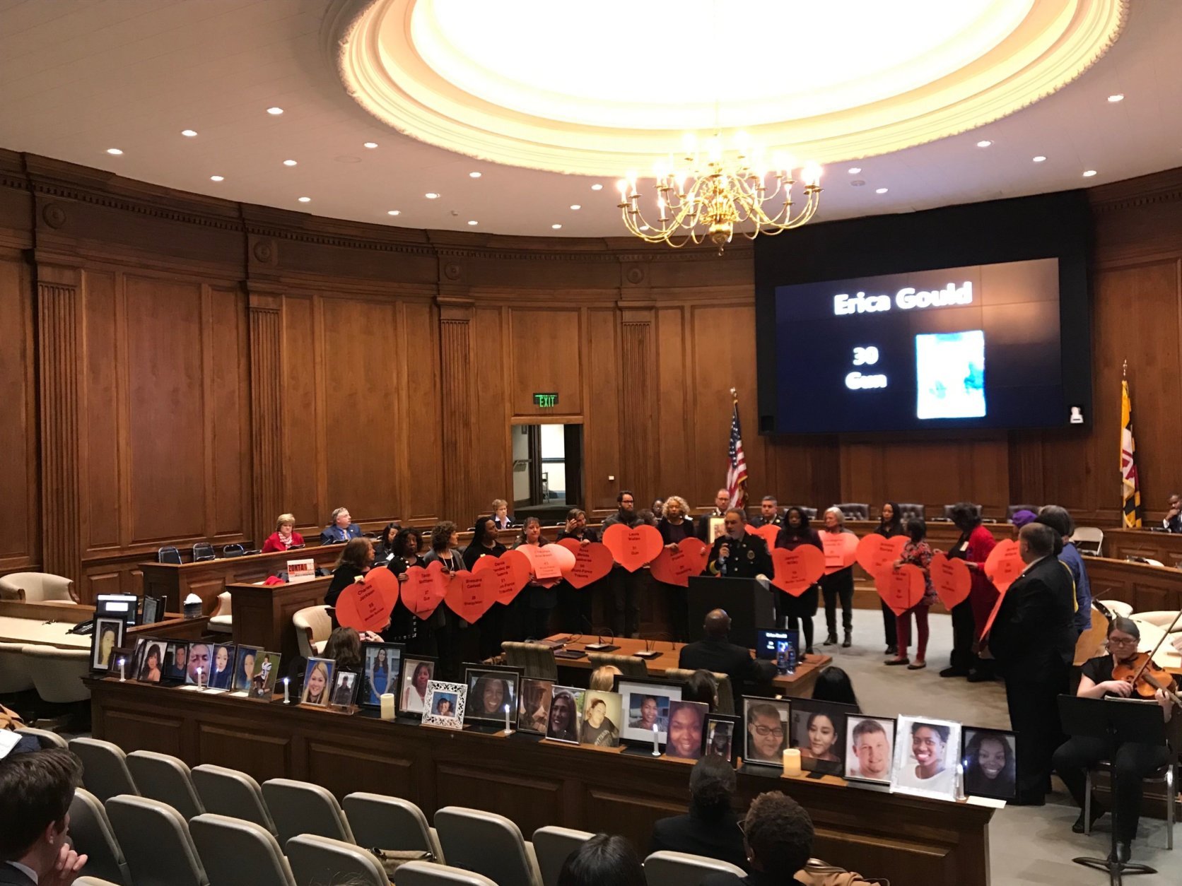 The names of domestic violence victims were called and participants at the ceremony displayed each name on red heart-shaped signs, which also indicated the victim's cause of death. Guns were used in 67 percent of the killings. (WTOP/Dick Uliano) 