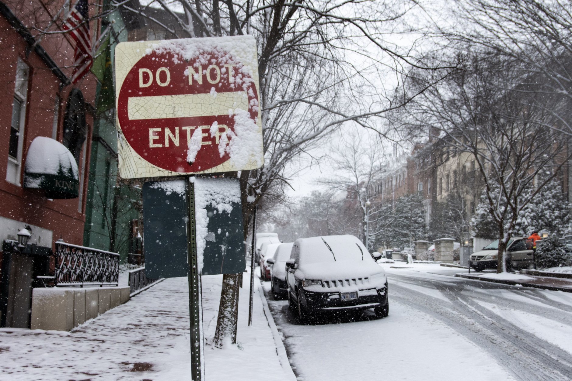 A snow-covered street sign near D.C.’s Dupont Circle on Wednesday morning. Normally busting with commuters at this time, traffic in this Connecticut Avenue neighborhood was light on Wednesday morning, with most residents indoors or salting sidewalks. (WTOP/Alejandro Alvarez)