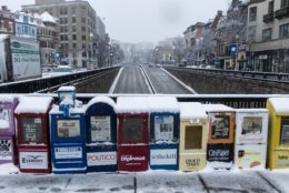 Newspaper stands in Dupont Circle, covered with snow. Visible is Connecticut Avenue looking northward. Most stores in the area were open as usual. (WTOP/Alejandro Alvarez)